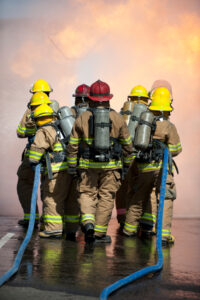 Fire training exercise Directed by officers in red helmets, two teams of firefighters attack a propane fire during a training exercise.